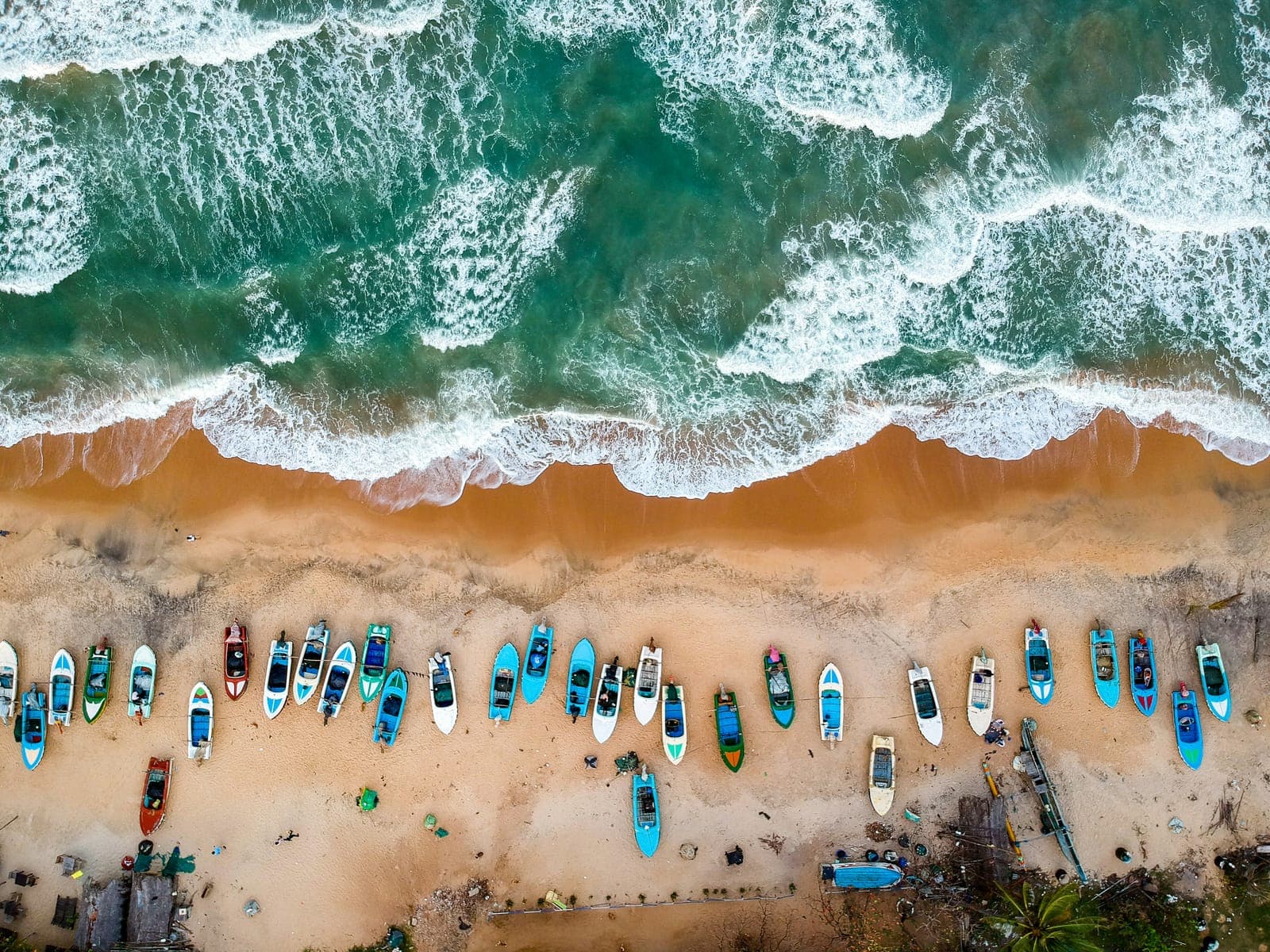 Aerial view of fishing boats lined along a Sri Lankan beach