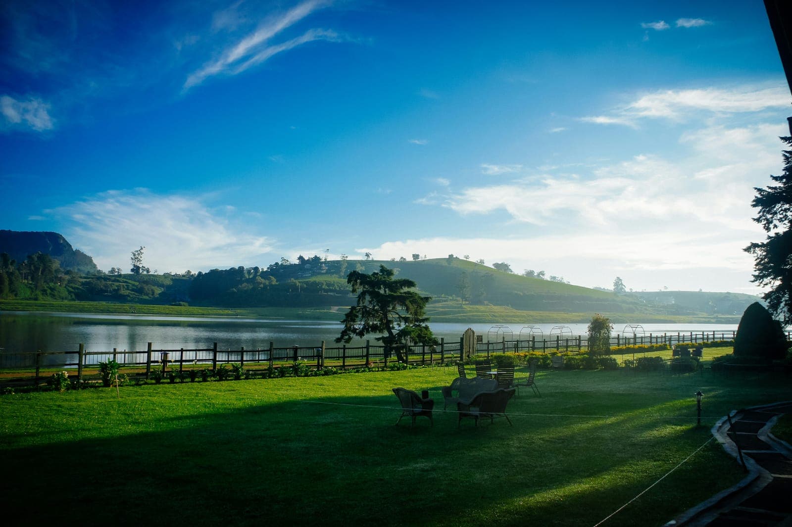 A calm highland lake and lawn under a wide blue sky at Nuwara Eliya